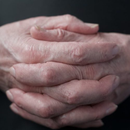 Close-up of senior adult hands showing texture and age in soft lighting.